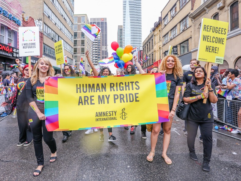 Amnesty International participants walk with a banner that says, Human rights are my pride, during Toronto's LGBTQ Pride Parade.