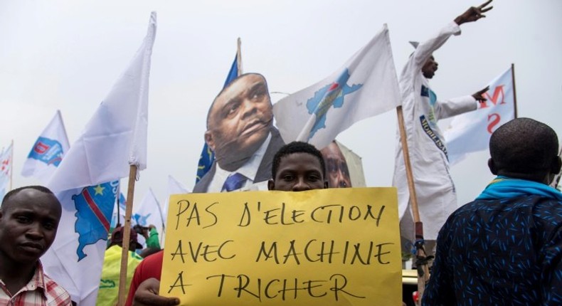 An opposition supporter holds a sign reading No election with a cheating machine -- there have been concerns about the use of electronic voting machines in DRC's poll