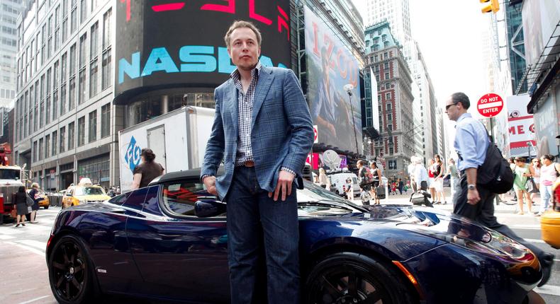 Elon Musk poses with a Tesla car in front of Nasdaq after its IPO