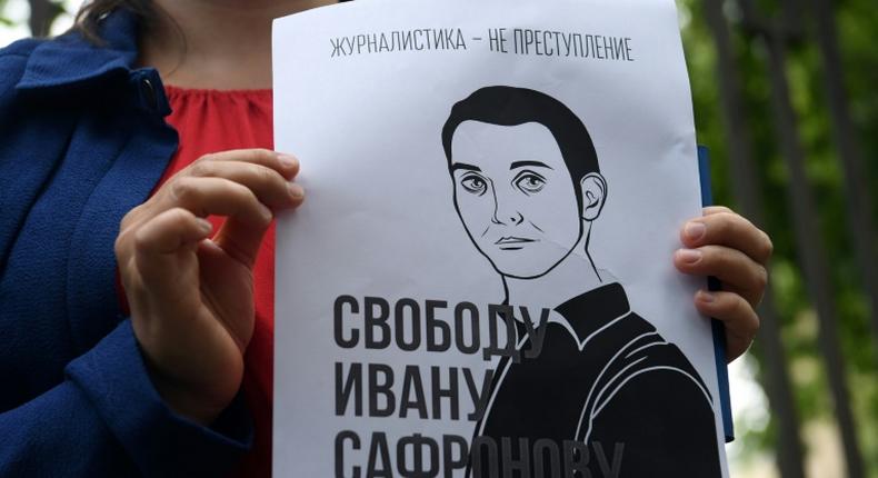 A woman holds a poster featuring an image of Ivan Safronov and the words Journalism is not a crime