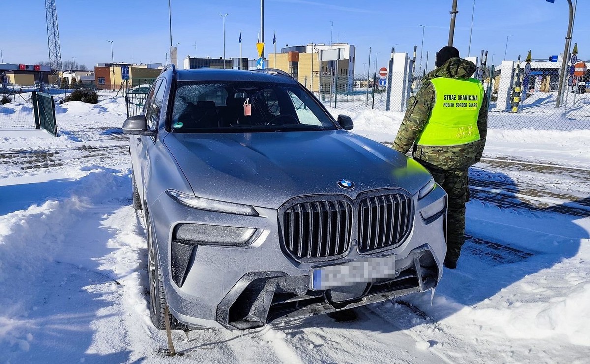 Luksusowe BMW X7 odzyskane przez Straż Graniczną na przejściu granicznym w Kuźnicy, obok funkcjonariusz w kamizelce odblaskowej