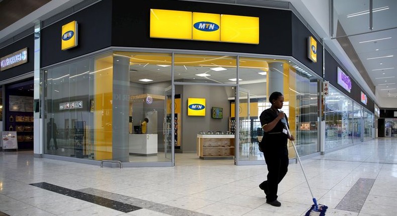 A worker sweeps past an outlet of South Africa's MTN Group in Johannesburg, February 23, 2016. REUTERS/Siphiwe Sibeko