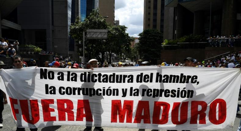 Supporters of Venezuelan opposition leader Juan Guaido hold a banner reading Maduro Out as they protest against President Nicolas Maduro in Caracas