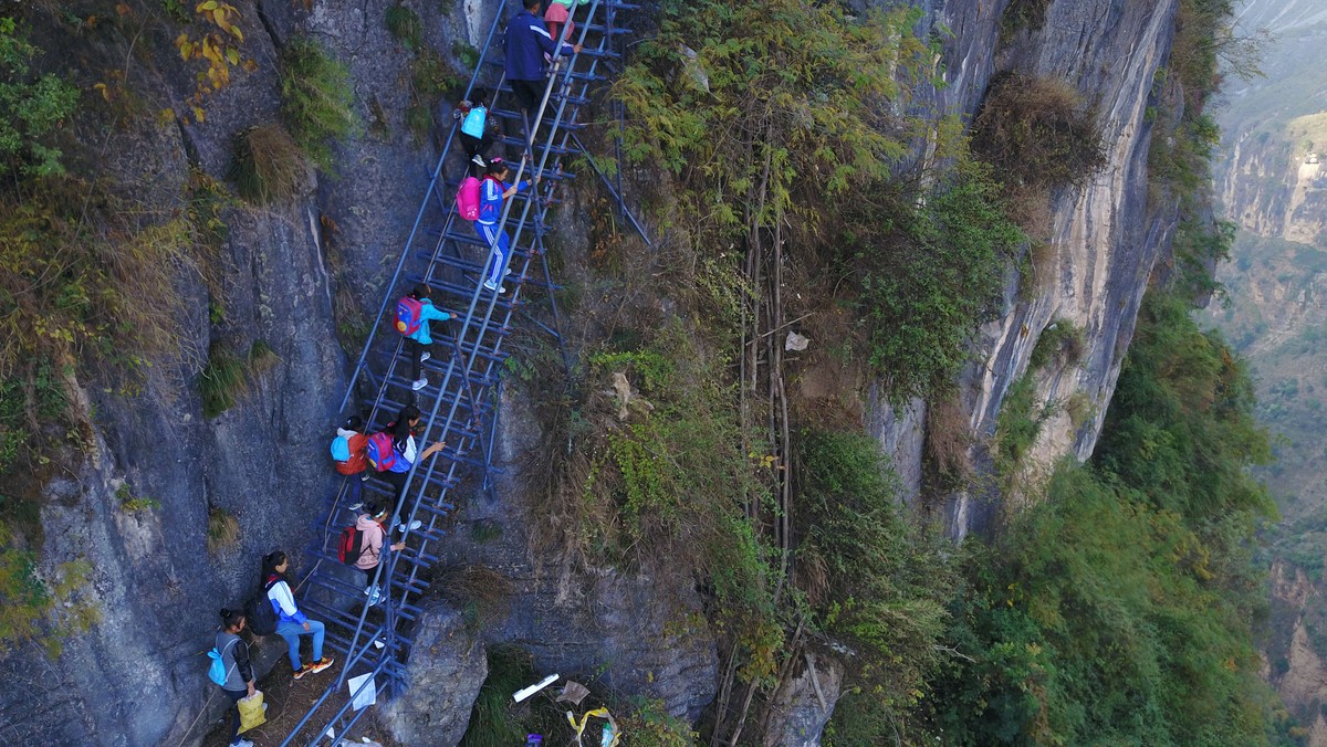 Students from "the cliff village" in Atule'er climb newly-constructed steel ladders after school to go home for holidays, in Liangshan