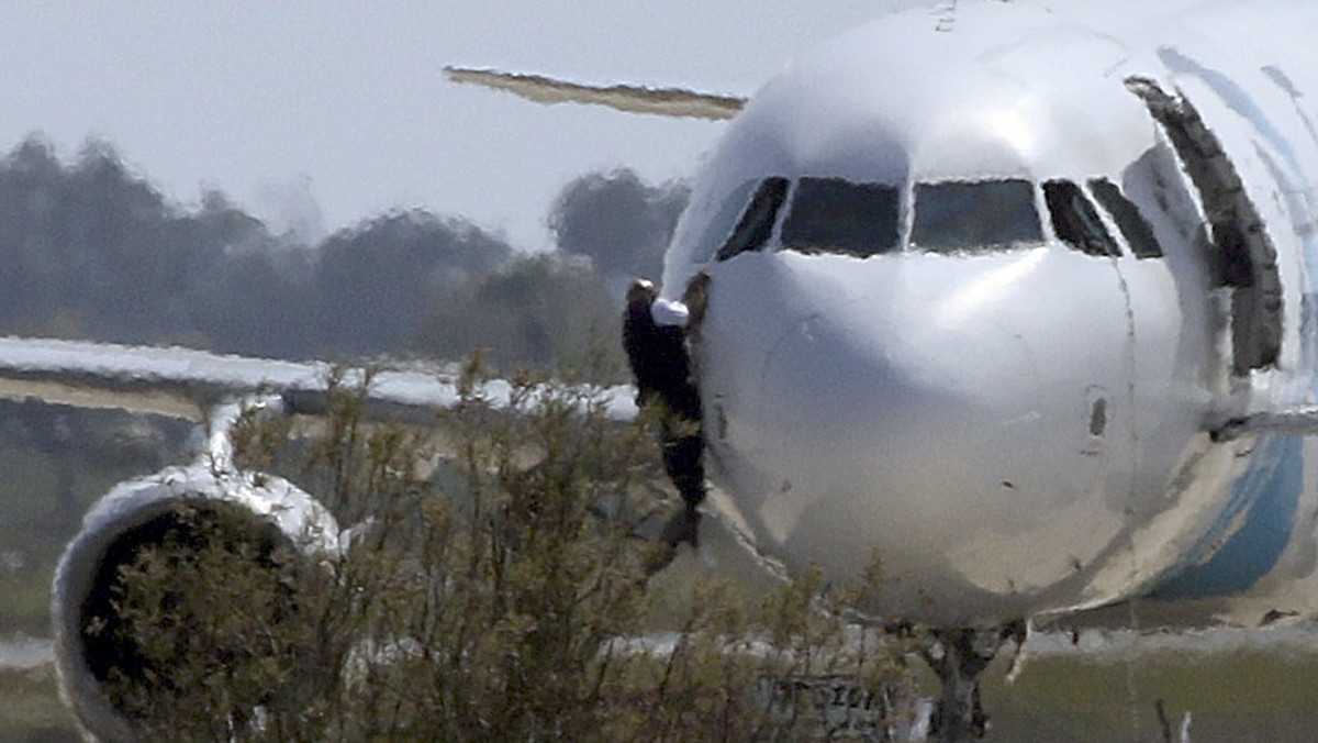 A man climbs out of the cockpit window of the hijacked Egyptair Airbus A320 at Larnaca Airport in Larnaca, Cyprus