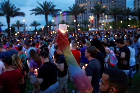 Man raises a candle during a vigil in memory of victims one day after a mass shooting in Orlando, Fl