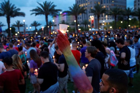 Man raises a candle during a vigil in memory of victims one day after a mass shooting in Orlando, Fl