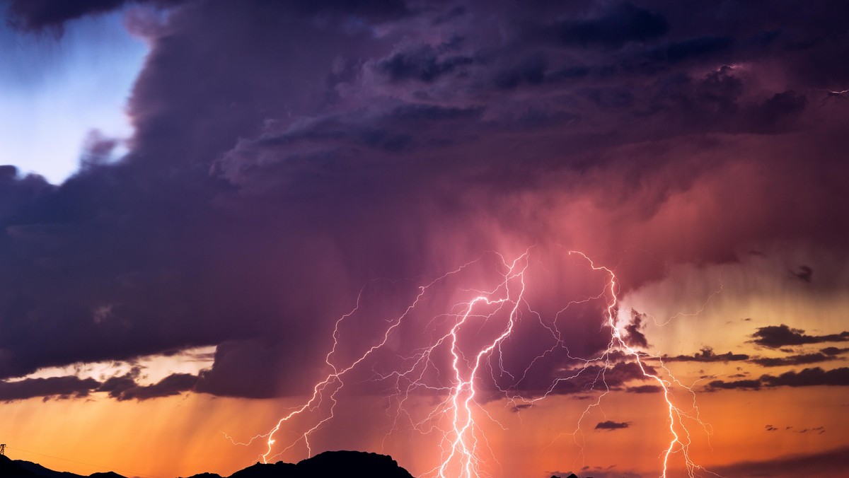 Lightning bolts strike from a sunset storm