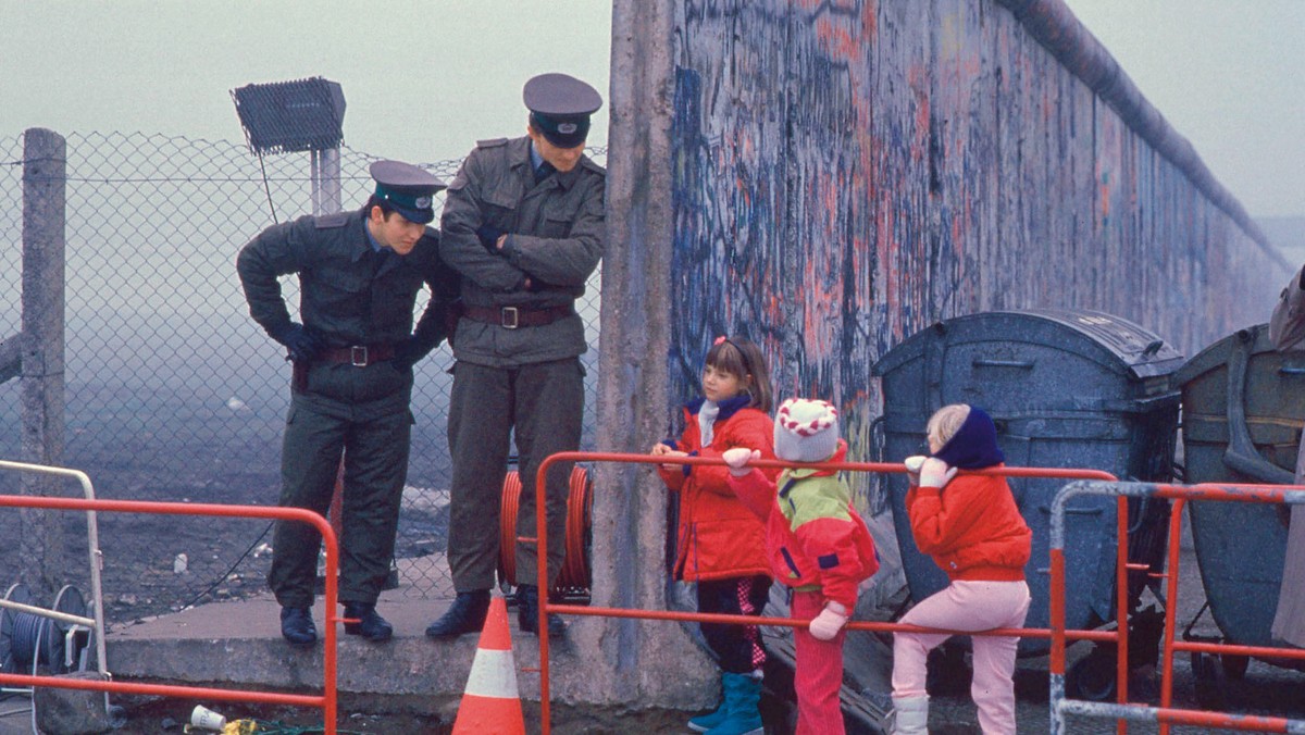 Dzieci z Berlina Zachodniego w drodze do szkoły przechodzą przez obalony mur berliński, 14 listopada 1989 r.