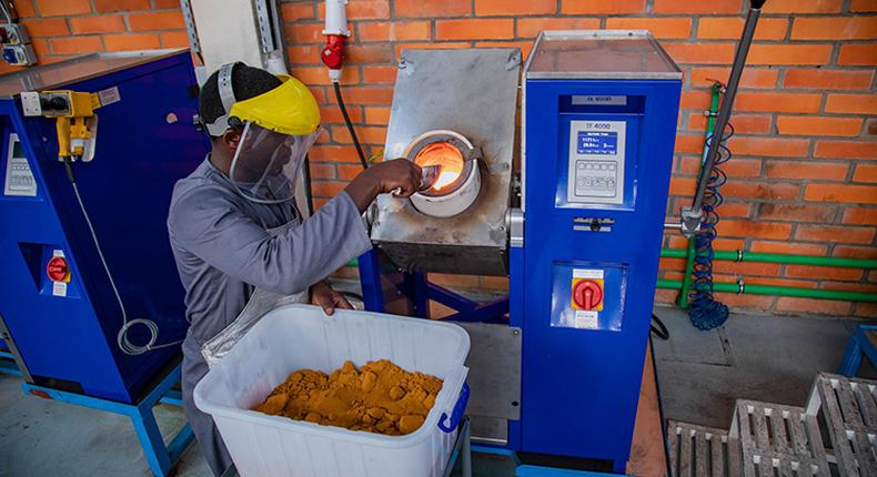 A worker at Aldango Gold Refinery puts gold powder into a high temperature heating device to melt.