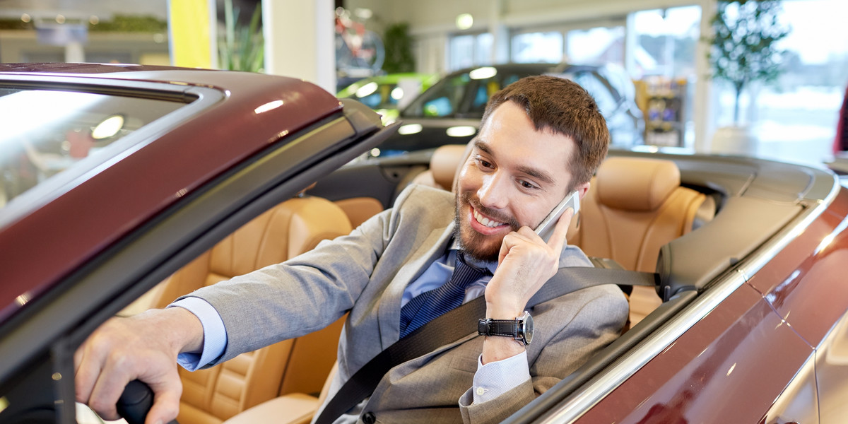 happy man sitting in car at auto show or salon