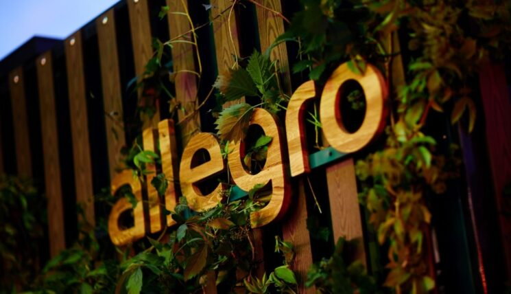 Drewniany logotyp Allegro przytwierdozny do drewnianej ściany. Na pie