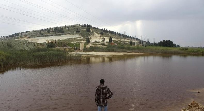 A man looks at acidic water flowing from the old mines in Riverlea, south of Johannesburg, February 8, 2011. 