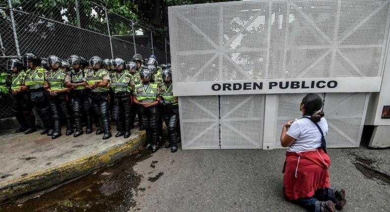 A woman kneels during a silent march by the opposition in a show of condemnation of the government of Venezuelan President Nicolas Maduro, in Caracas