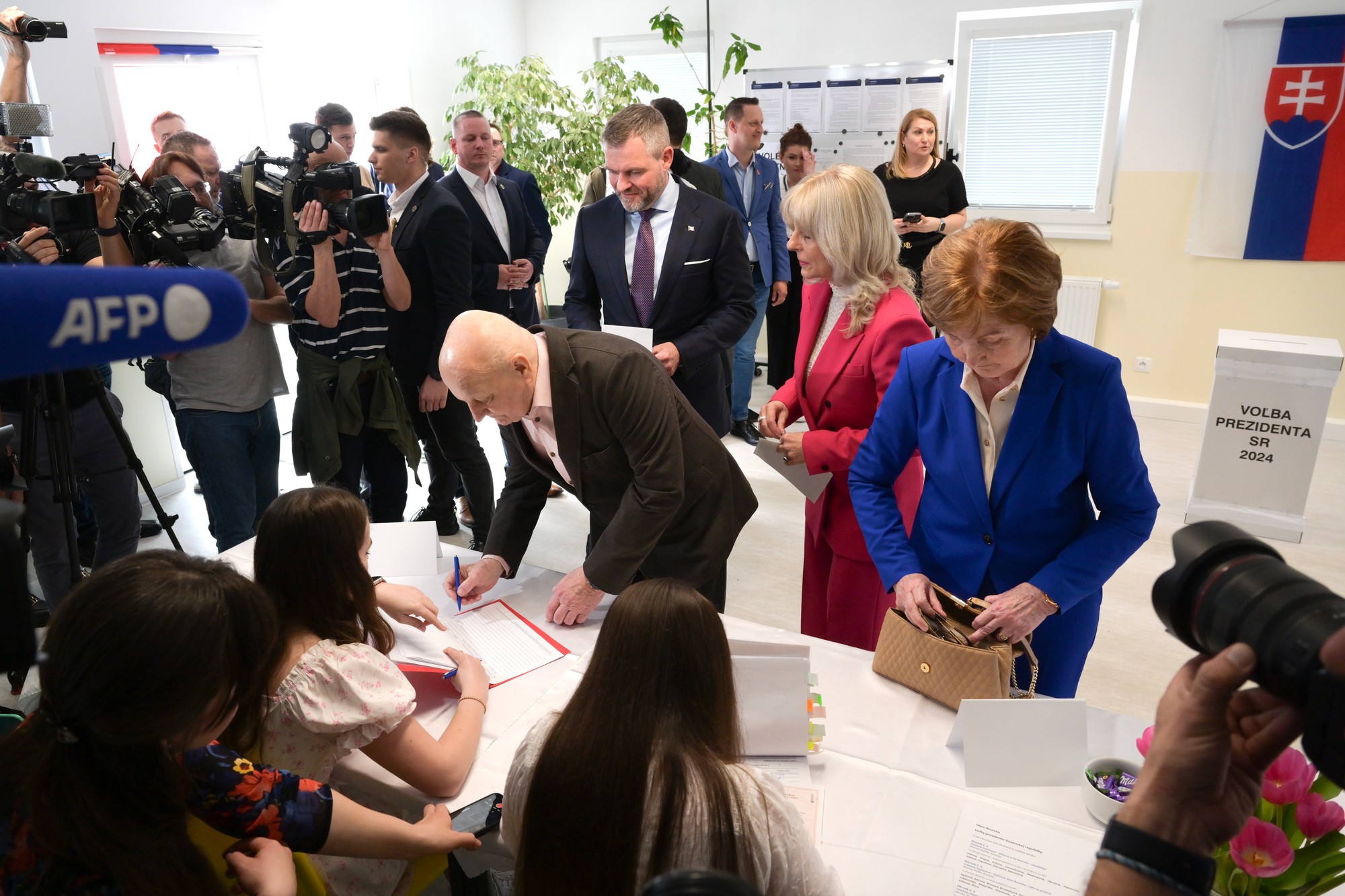 Vľavo v pozadí kandidát na prezidenta SR PeterPellegrini, druhá sprava sestra a jeho rodičia pri registrácii vo volebnej miestnosti v druhom kole prezidentských volieb 6. apríla 2024 v miestnej škole v obci Rovinka.