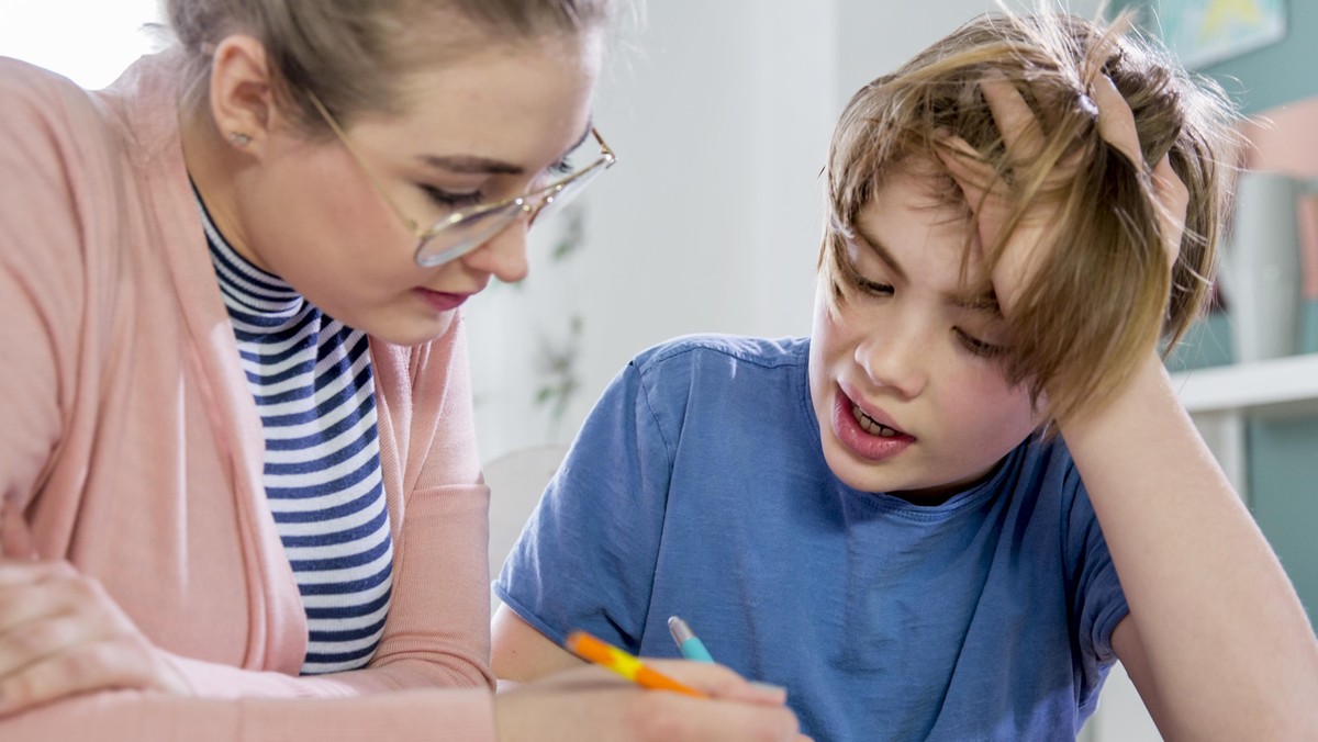 Private tutoring lesson for 10 years old blonde primary school boy while doing his homework together with female tutor in her twenties.