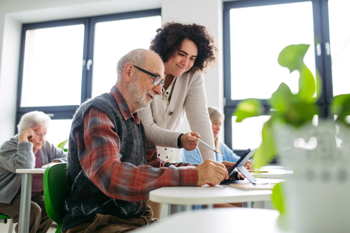 Senior,Man,Learning,Digital,Skills,With,Tutor,Support,In,Community