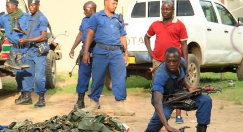 Burundian police officers collect a cache of weapons recovered from suspected fighters after clashes in the capital Bujumbura, Burundi December 12, 2015.