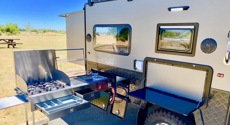 The full outdoor kitchen has a stainless steel chopping board, prep deck, and pantry.