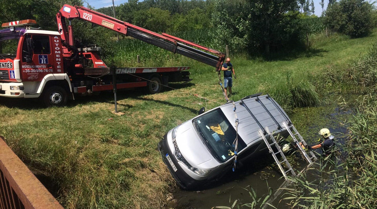 A tűzoltók darujára volt szükség a patakba csúszott autó kiemeléséhez. A sofőr az anyósülésen át tudott kimenekülni