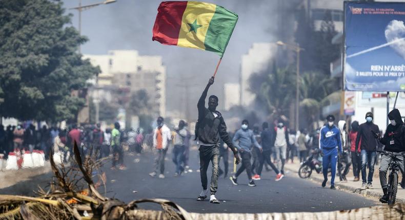 A demonstrator waves a Senegalese national flag during protests in support of main opposition leader and former presidential candidate Ousmane Sonko in Dakar, Senegal, Wednesday, March 3, 2021.