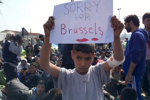 A refugee boy holds up placard reading Sorry for Brussels as refugees and migrants take part in a 