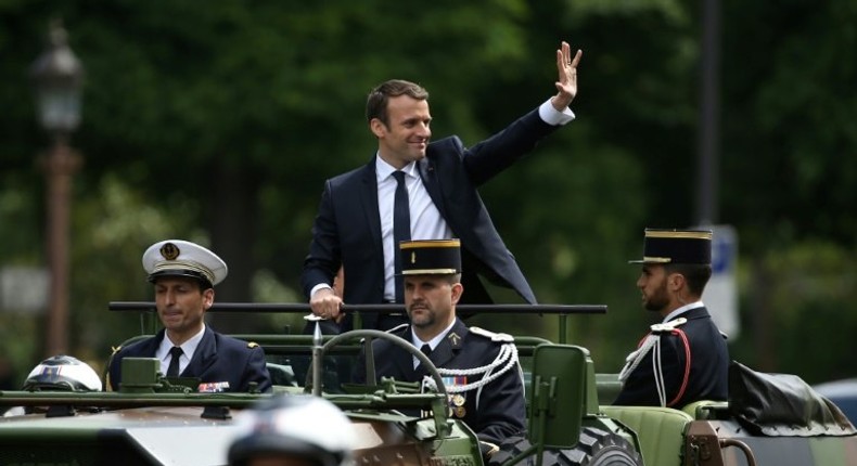 French President Emmanuel Macron (C) waves as he parades in a car on the Champs Elysees avenue after his formal inauguration ceremony on May 14, 2017 in Paris