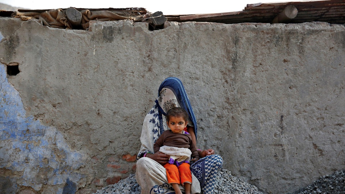 A woman rests with her child while working as a day labourer in Delhi