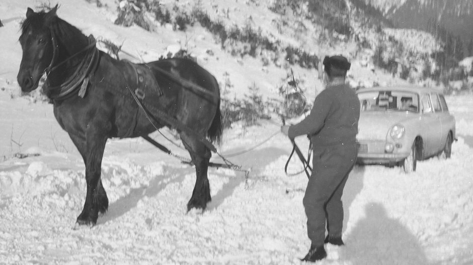 Zakopane, lata 70. Zaprzęganie konia do samochodu unieruchomionego na drodze w górskiej dolinie