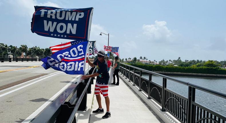 Trump supporter holds a Trump won flag outside of Mar-a-Lago.