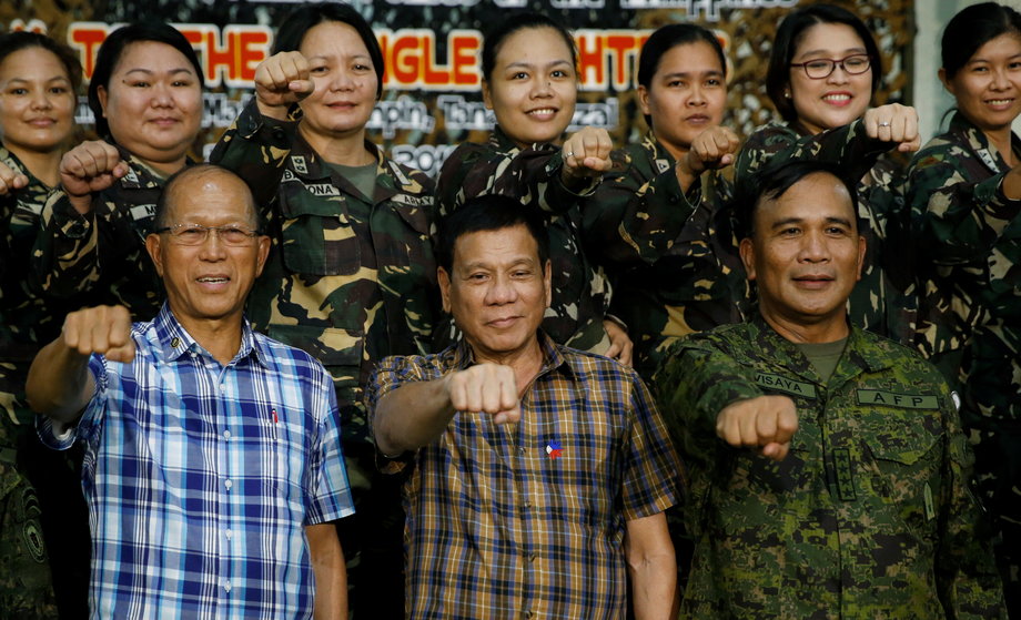 Philippine President Rodrigo Duterte makes a "fist bump," his presidential campaign gesture, with defense officials and soldiers during a visit at Capinpin military camp in Tanay, Philippines, August 24, 2016.