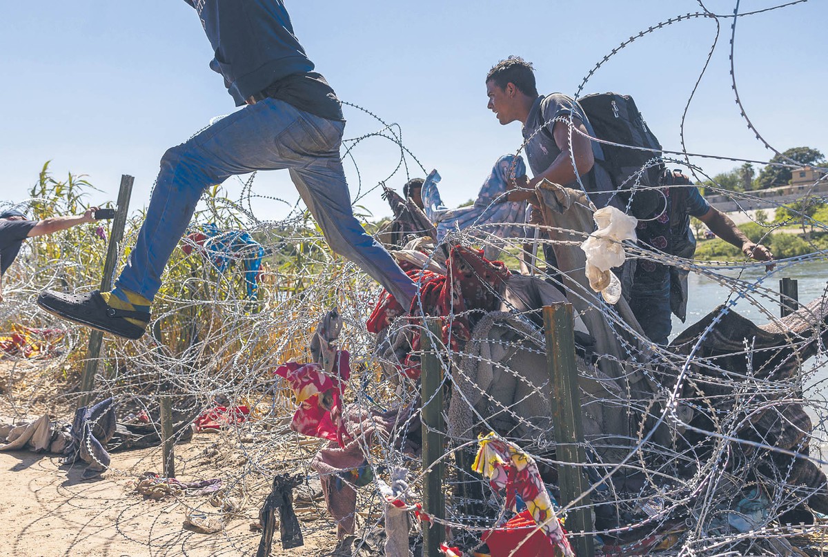 Migranci przedzierający się przez drut kolczasty na granicy z Meksykiem w okolicach Eagle Pass w Teksasie, 28 września 2023 r.
