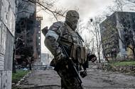 Rosyjski żołnierz stoi na tle płonącego bloku mieszkalnego w centrum Mariupola. Ukraina, 18.04.2022