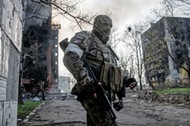 Rosyjski żołnierz stoi na tle płonącego bloku mieszkalnego w centrum Mariupola. Ukraina, 18.04.2022