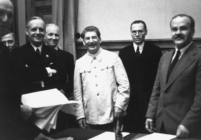 Minister spraw zagranicznych ZSRR Wiaczesław Mołotow (z prawej) i minister spraw zagranicznych Niemiec Joachim von Ribbentrop (z lewej) podczas podpisywania paktu o nieagresji między ZSRR a Niemcami z Józefem Stalinem (w środku). Moskwa, 23 sierpnia 1939 r.