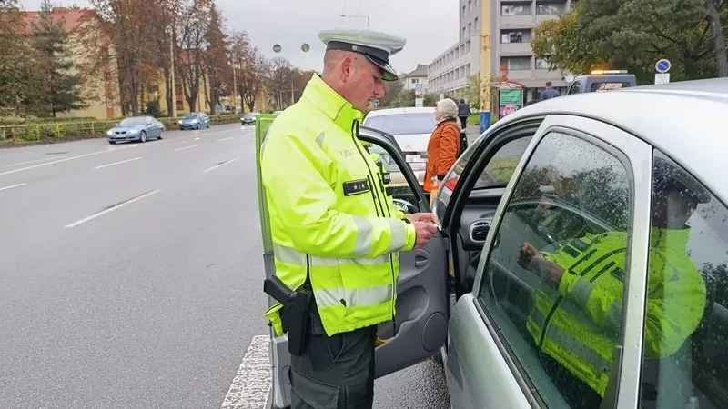 Detailný záber na policajta, ktorý kontroluje doklady vodiča počas bežnej cestnej kontroly.  