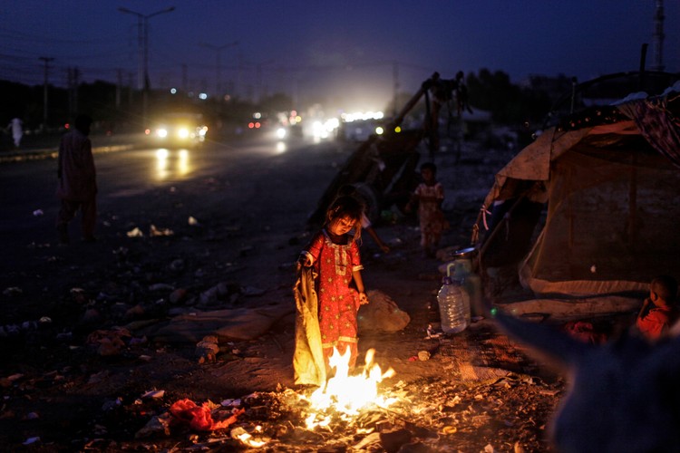 Bezdomna dziewczynka koczująca w osiedlu przy autostradzie stoi przy ognisku. Tak chroni się przed moskitami