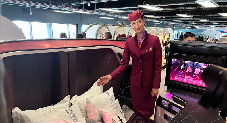 A Qatar Airways flight attendant and a QSuite configured as a double bed.Pete Syme/Business Insider