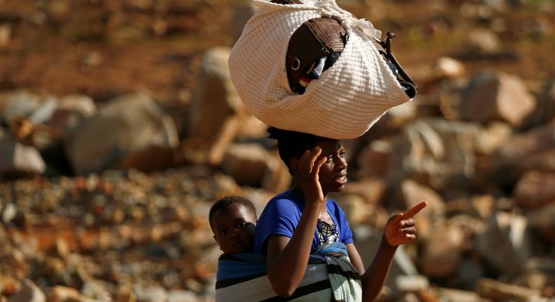 A survivor of Cyclone Idai carries her baby as she moves to higher ground at Ngangu suburb in Chimanimani.