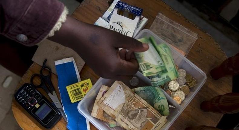 A shopkeeper puts money in her cash box at her shop in Hillcrest west of Durban, South Africa, January 11, 2016. 