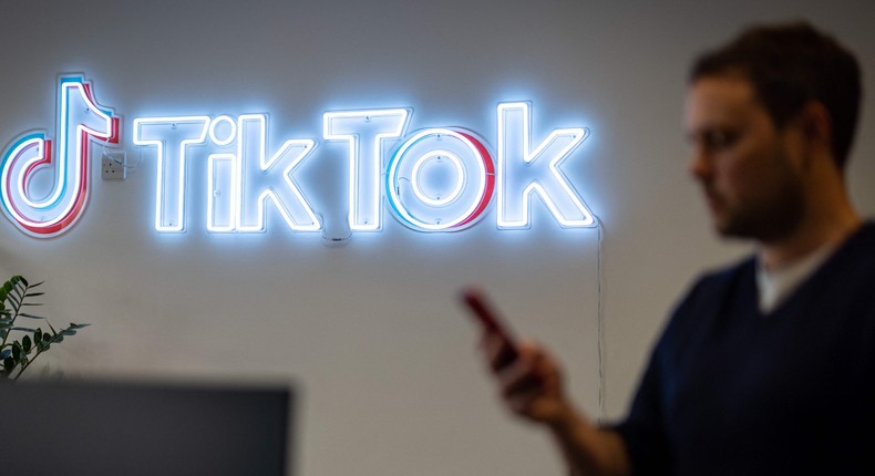 BuzzFeed News reported Monday that TikTok's owner ByteDance had scraped content from Instagram and Snapchat in 2017 to create fake accounts on Flipagram, TikTok's predecessor. Here, a TikTok employee looks at his mobile phone as he walks past the logo of TikTok in a London office on February 9, 2022.