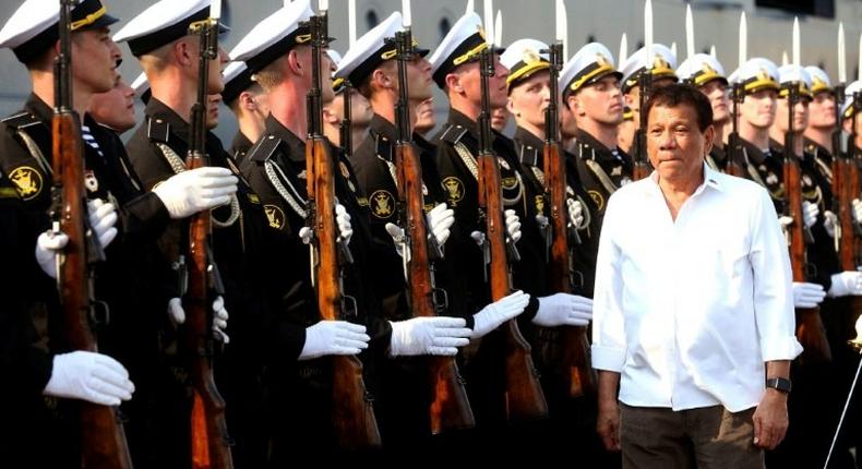 Philippine President Rodrigo Duterte (R) walks past honour guards during a visit to the Russian Guided Missile Cruiser Varyag docked at the Port of Manila on April 21, 2017
