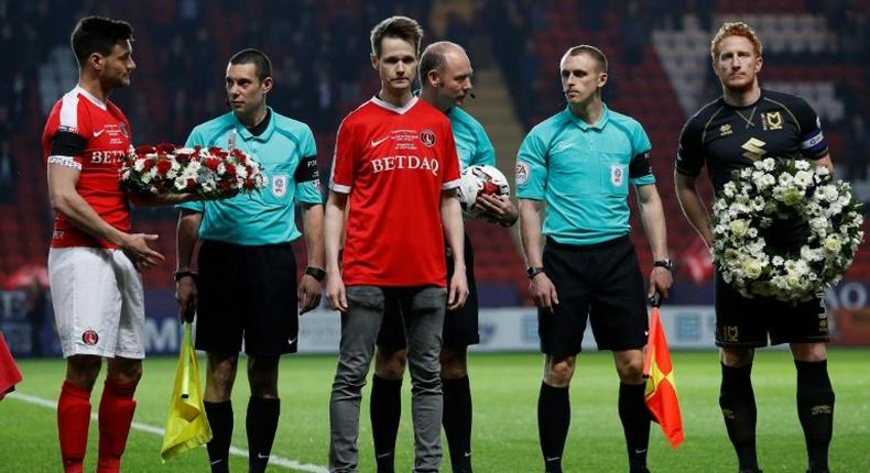 John Palmer (C), brother of Charlton Athletic season ticket holder, PC Keith Palmer, who was killed in the March 22, 2017 Westminster terror attack, greets match officials and players at The Valley Stadium in London