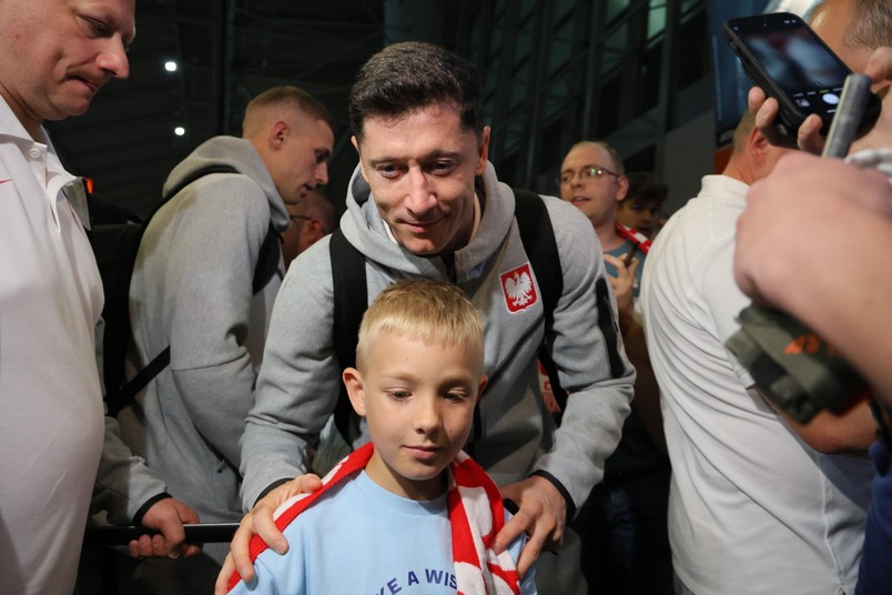 Kapitan piłkarskiej reprezentacji Polski Robert Lewandowski (C) z młodym kibicem podczas powitania na warszawskim lotnisku Okęcie