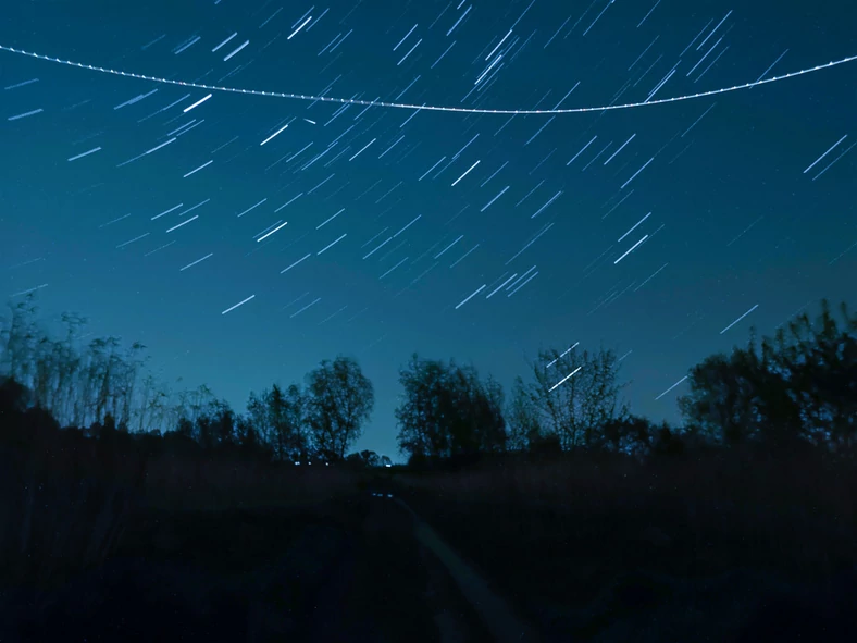 Na zdjęciu oprócz świetlistych torów gwiazd uchwycony został także ślad po samolocie oraz niewielki meteor