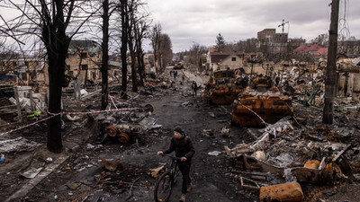 A man pushes his bike through debris and destroyed Russian military vehicles on a street on April 06, 2022 in Bucha, Ukraine.