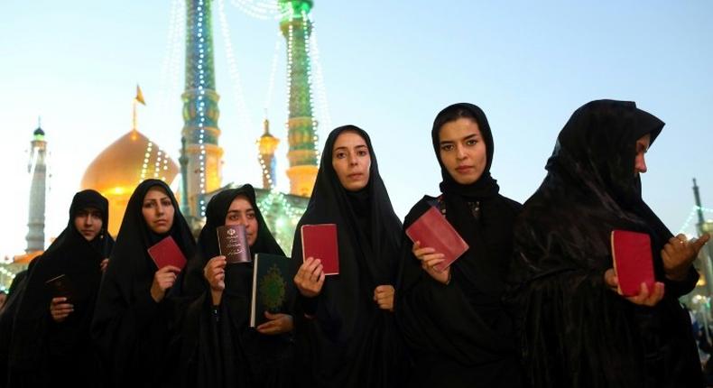 Iranian women hold their IDs as they wait to vote at the Massoumeh shrine in the holy city of Qom on May 19, 2017