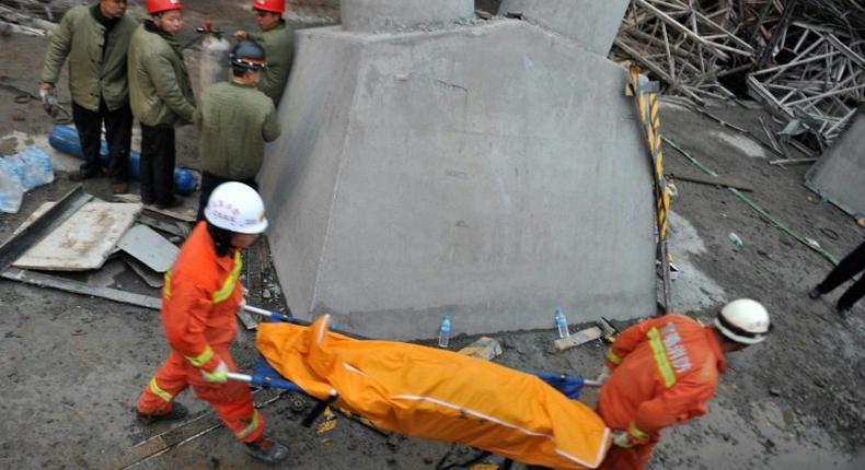 Workers carry a body on a stretcher from the remains of a collapsed platform in a cooling tower at a power station at Fengcheng in China's Jiangxi province on November 24, 2016