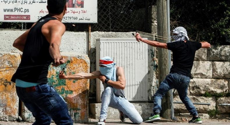 Palestinian protesters use slingshots to hurl stones towards Israeli security forces during clashes in the West Bank town of Bethlehem on April 21, 2017, in solidarity with the hunger striking prisoners