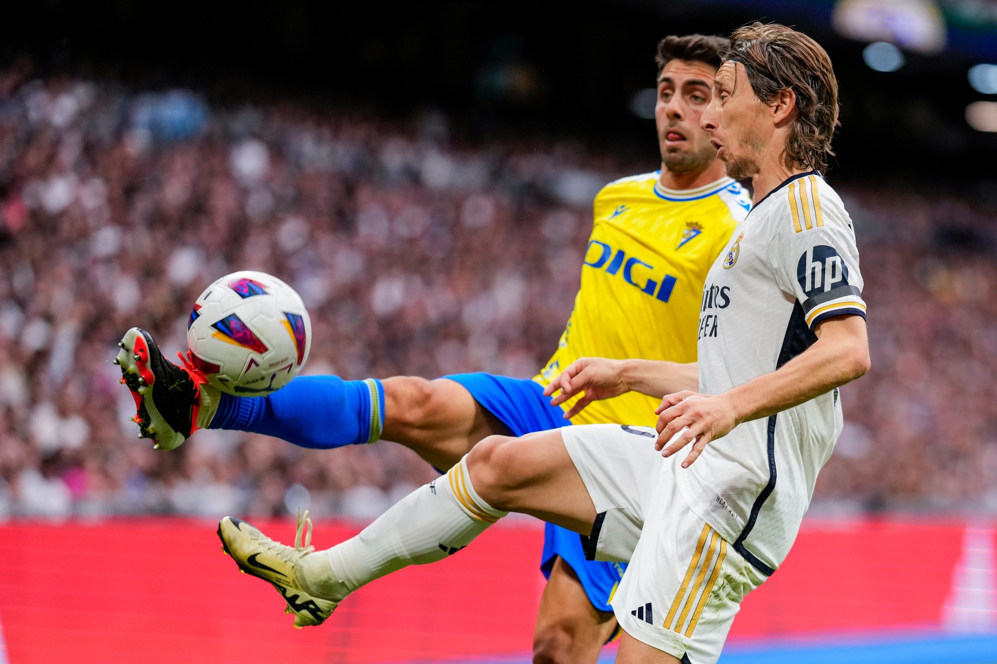 Futbalista Realu Madrid Luka Modrič (vpravo) a hráč Cádizu Rubén Sobrino bojujú o loptu.